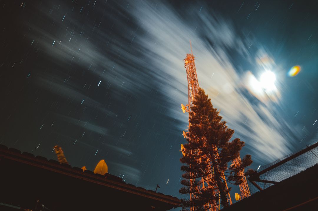 Telecommunication Tower under Cloudy Night Sky with Moving Stars - Free Images, Stock Photos and Pictures on Pikwizard.com