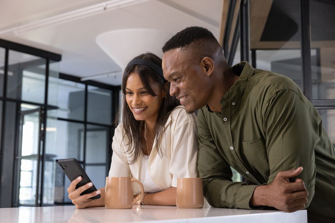 A Diverse Colleagues Sharing Content on Smartphone in Modern Office Break Room