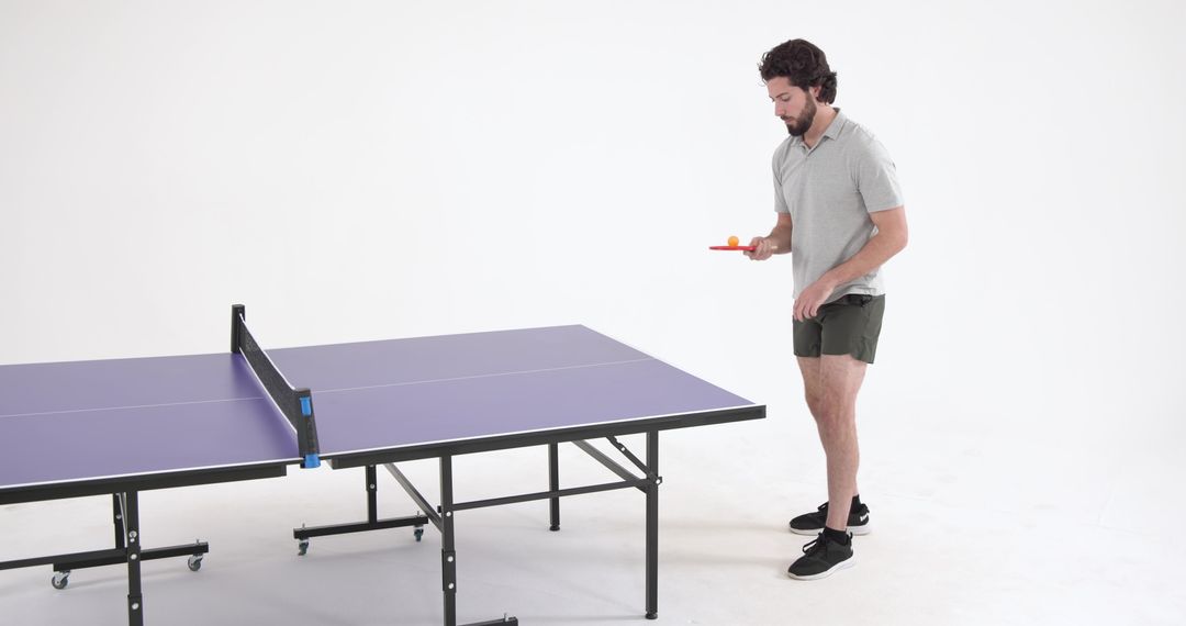 Man Balancing Table Tennis Ball on Paddle in Studio Setting