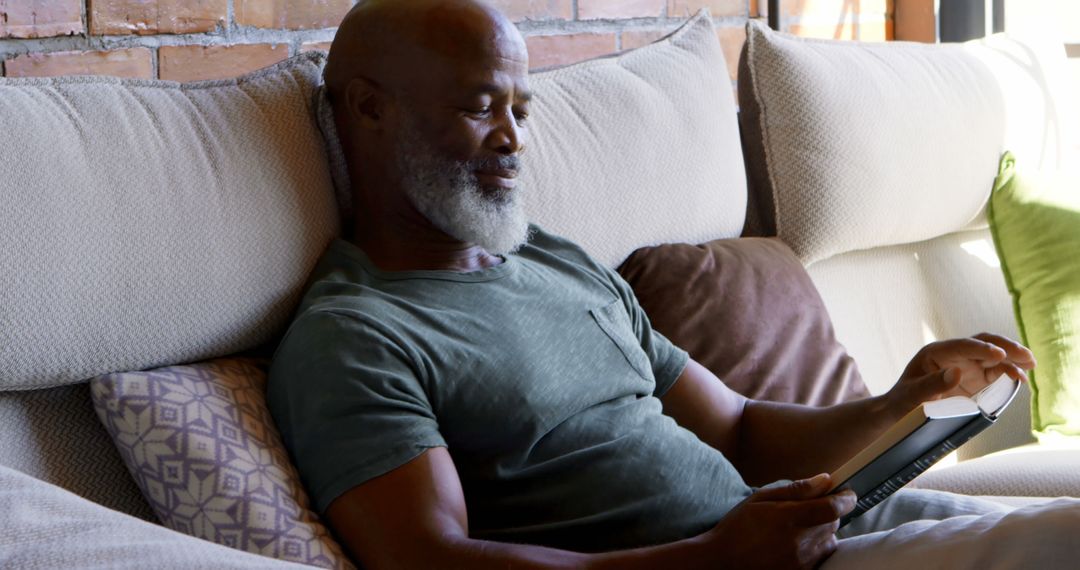 Relaxed Elderly Man Reading Tablet on Comfortable Sofa at Home - Free Images, Stock Photos and Pictures on Pikwizard.com