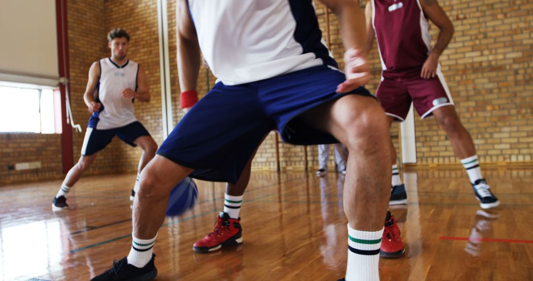 Basketball players in mid-game action indoors on wooden floor - Free Images, Stock Photos and Pictures on Pikwizard.com