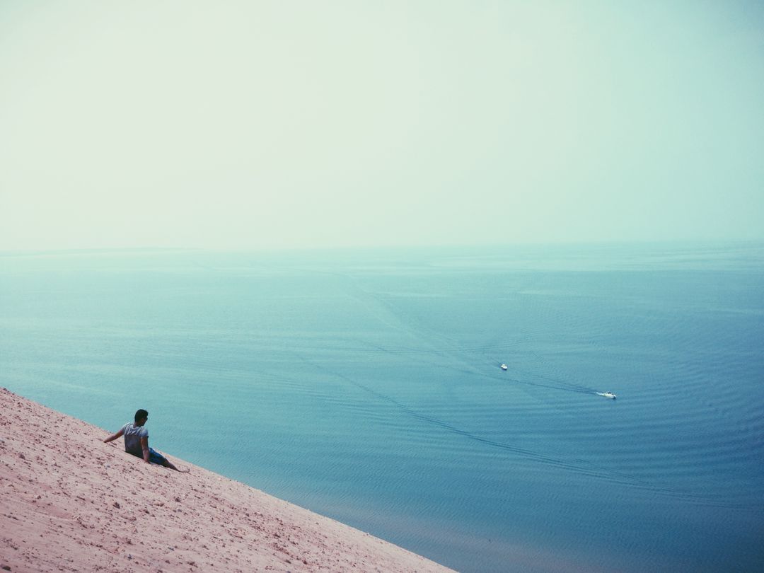 Man Relaxing on Sand Dune Overlooking Tranquil Sea - Free Images, Stock Photos and Pictures on Pikwizard.com