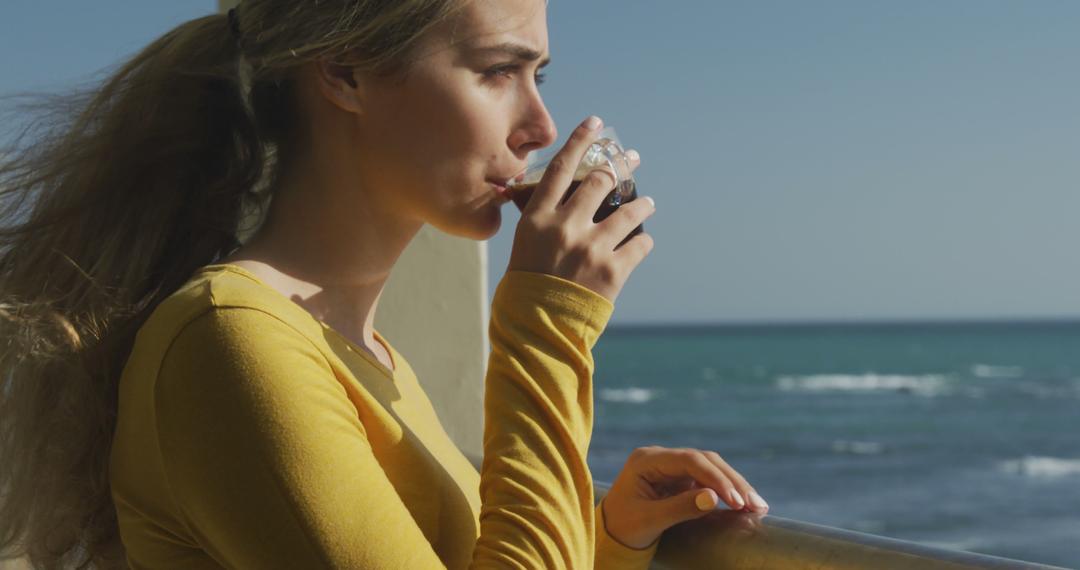 Woman Drinking Coffee by the Sea with Wind Blowing - Free Images, Stock Photos and Pictures on Pikwizard.com