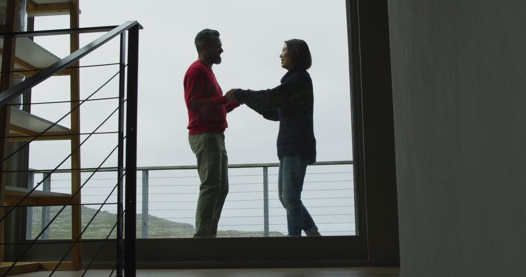 Happy Mature Couple Holding Hands in Modern House by Window - Free Images, Stock Photos and Pictures on Pikwizard.com