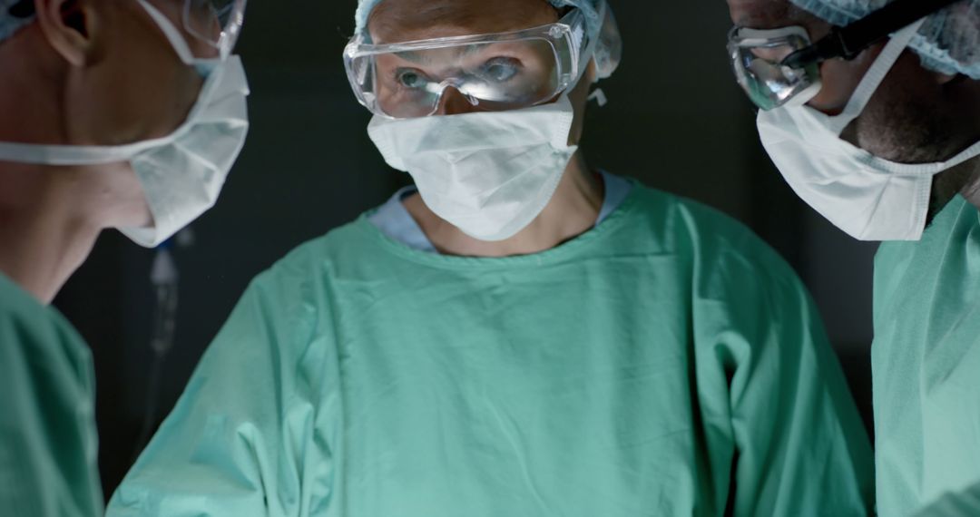 Focused diverse surgeons wearing face masks during surgery in operating room - Free Images, Stock Photos and Pictures on Pikwizard.com