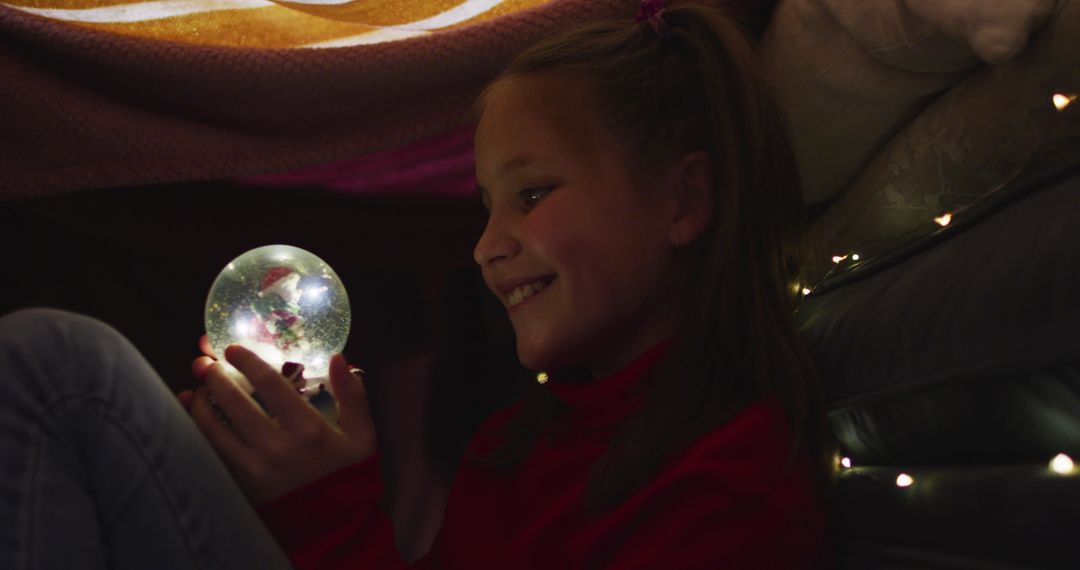 Girl Enjoying Magical Moment with Snow Globe During Christmas