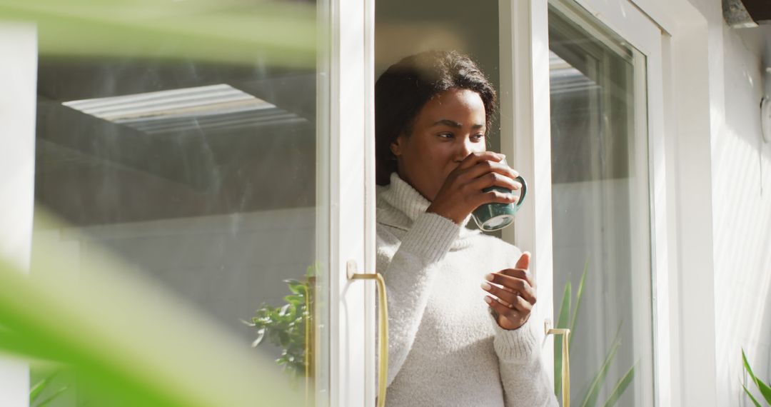 Woman Enjoying Morning Coffee by Window in Cozy Sweater - Free Images, Stock Photos and Pictures on Pikwizard.com