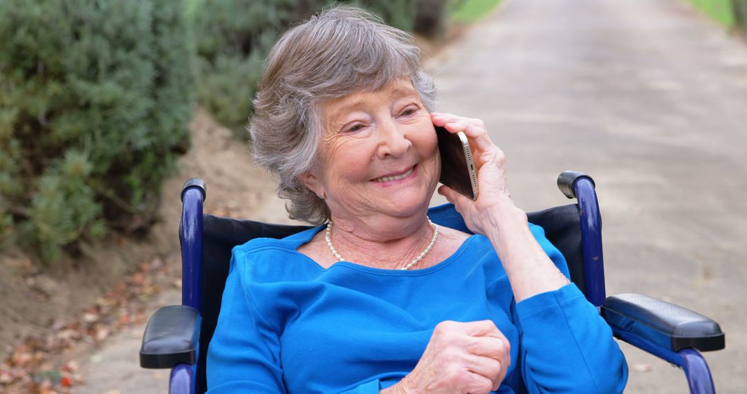 Senior Woman in Blue Outfit Sitting in Wheelchair Talking on Mobile Phone Outdoors - Free Images, Stock Photos and Pictures on Pikwizard.com