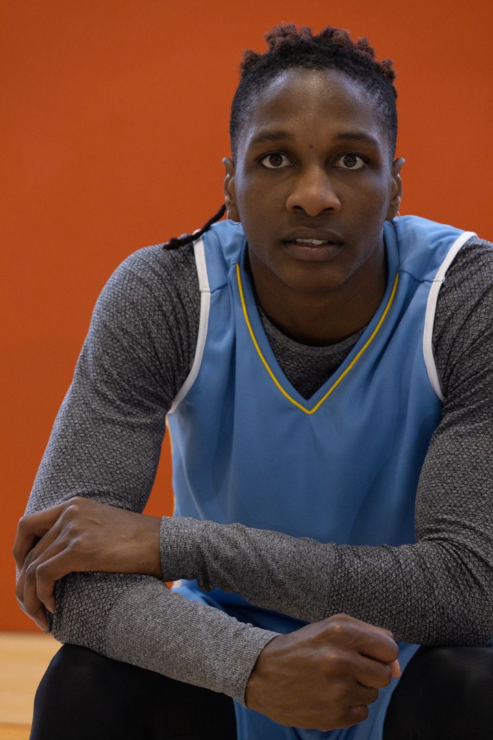 Athlete Crouching in Basketball jersey Shows Determination in Gym