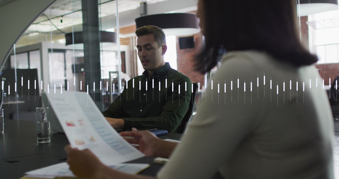 Coworkers Discussing Reports in Modern Office with Graph Overlay