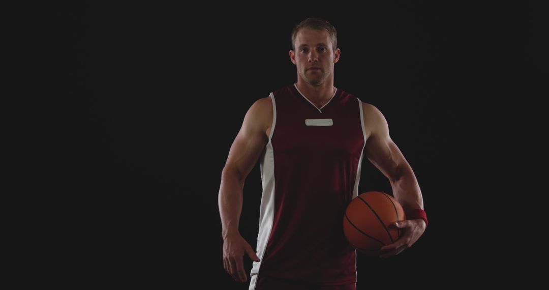 Basketball Player Holding Ball Against Dark Background - Free Images, Stock Photos and Pictures on Pikwizard.com