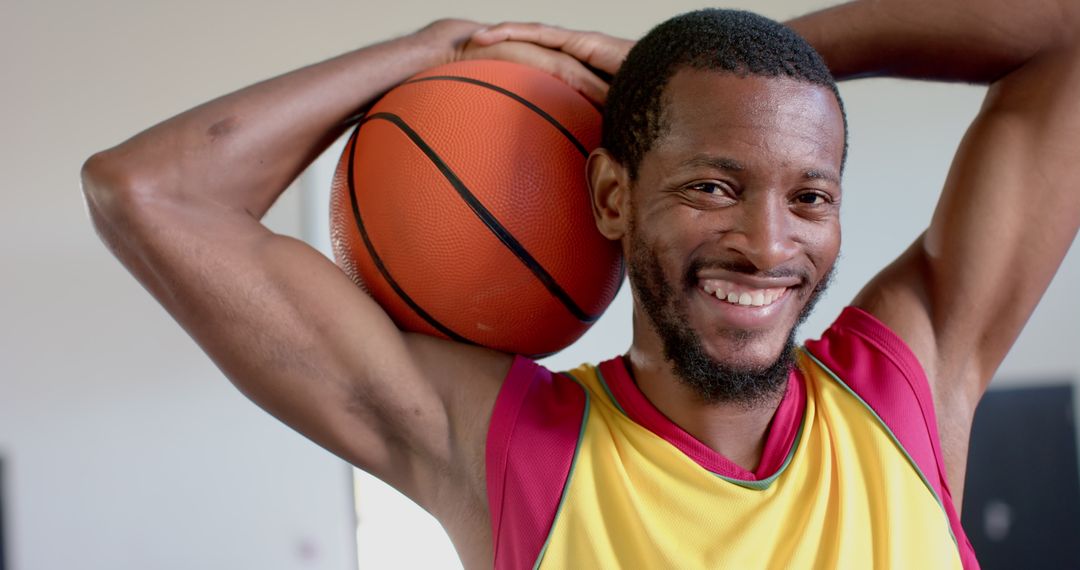 Smiling Athlete Poses with Basketball in Urban Gym