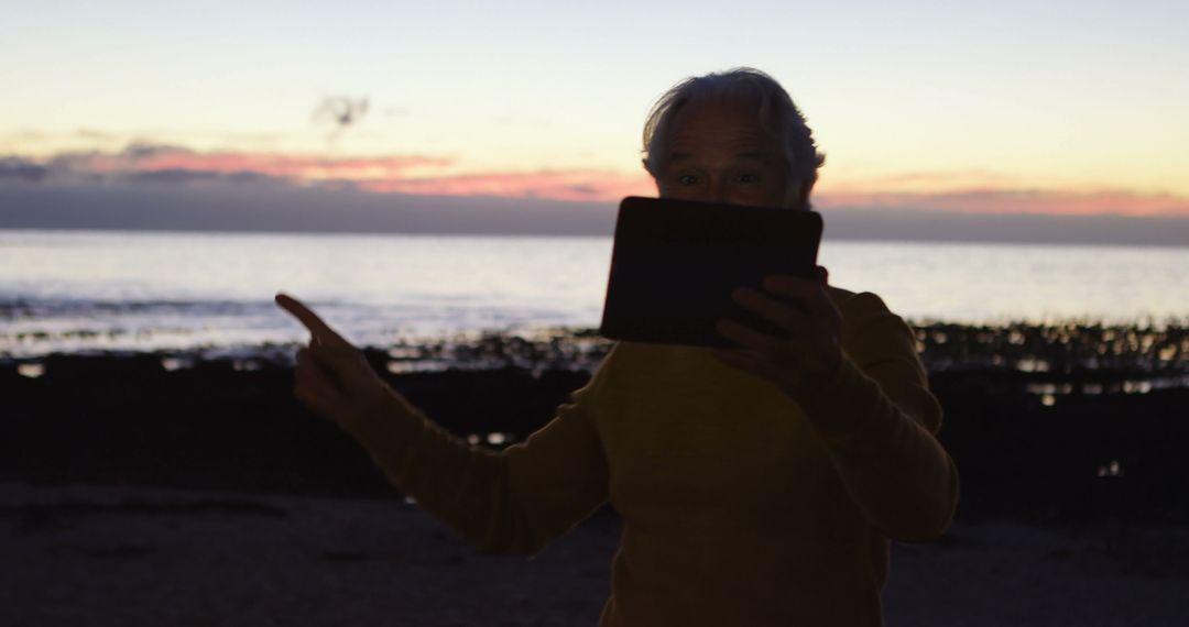 Elderly Person Enjoying Sunset on Beach with Tablet - Free Images, Stock Photos and Pictures on Pikwizard.com