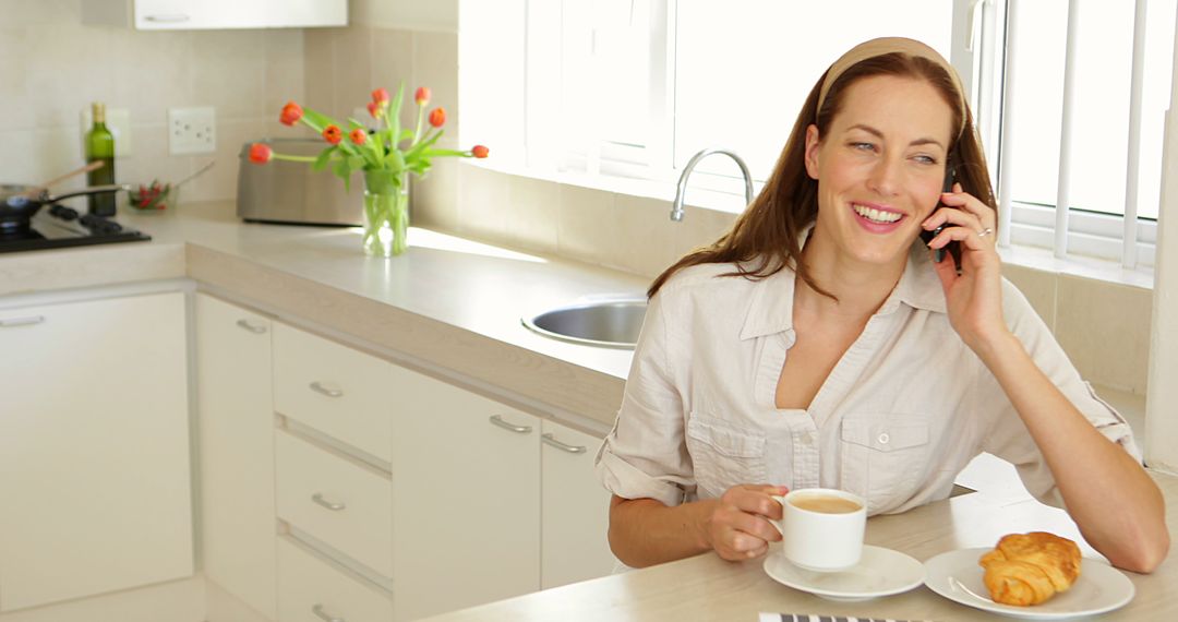 Smiling Woman Talking on Phone While Having Breakfast in Modern Kitchen - Free Images, Stock Photos and Pictures on Pikwizard.com