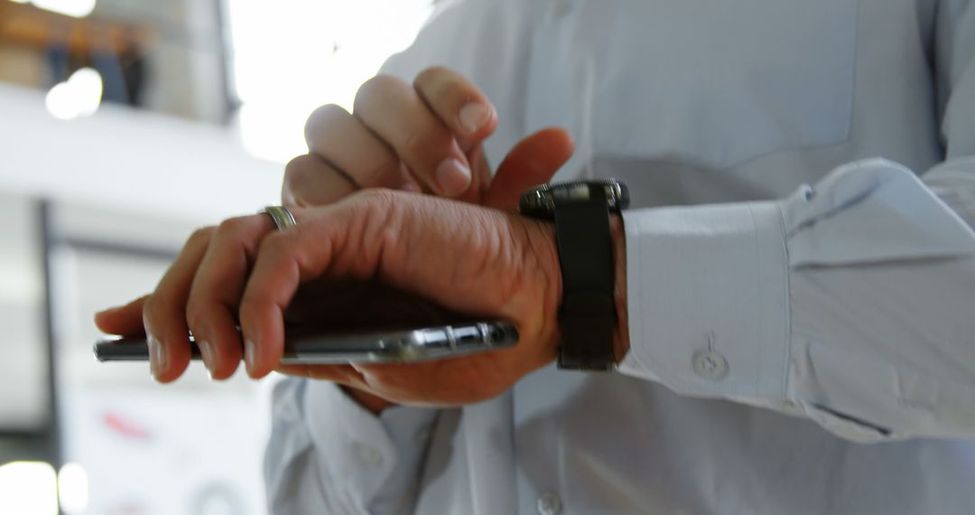 Businessman Using Smartwatch and Smartphone in Office - Free Images, Stock Photos and Pictures on Pikwizard.com