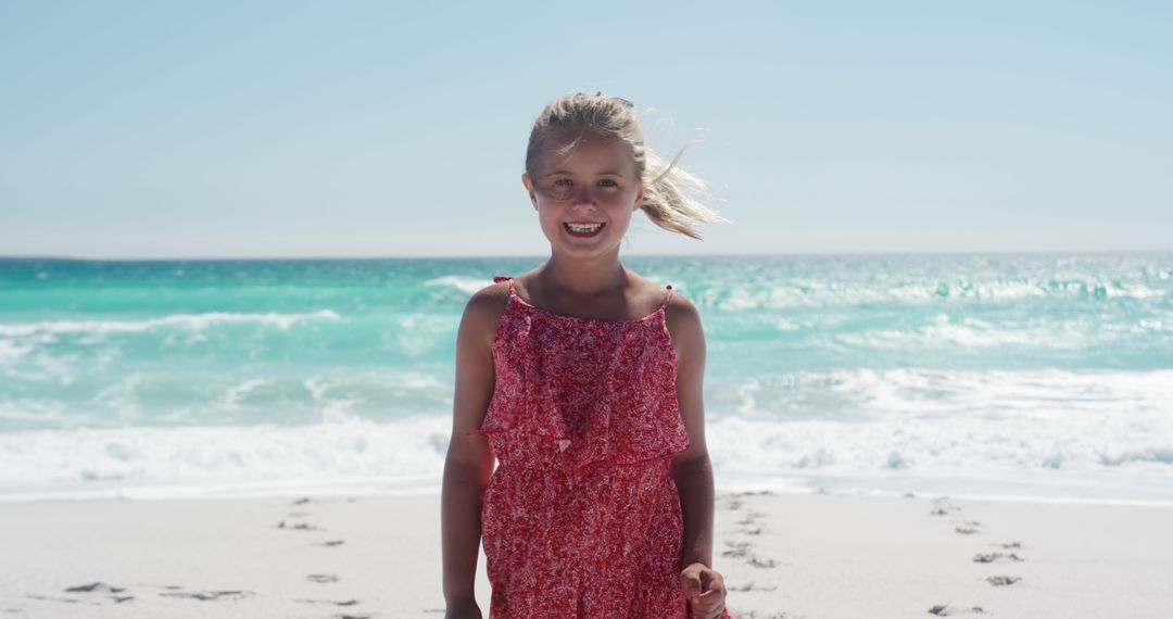 Smiling Girl in Red Dress Enjoying Sunny Beach Day - Free Images, Stock Photos and Pictures on Pikwizard.com