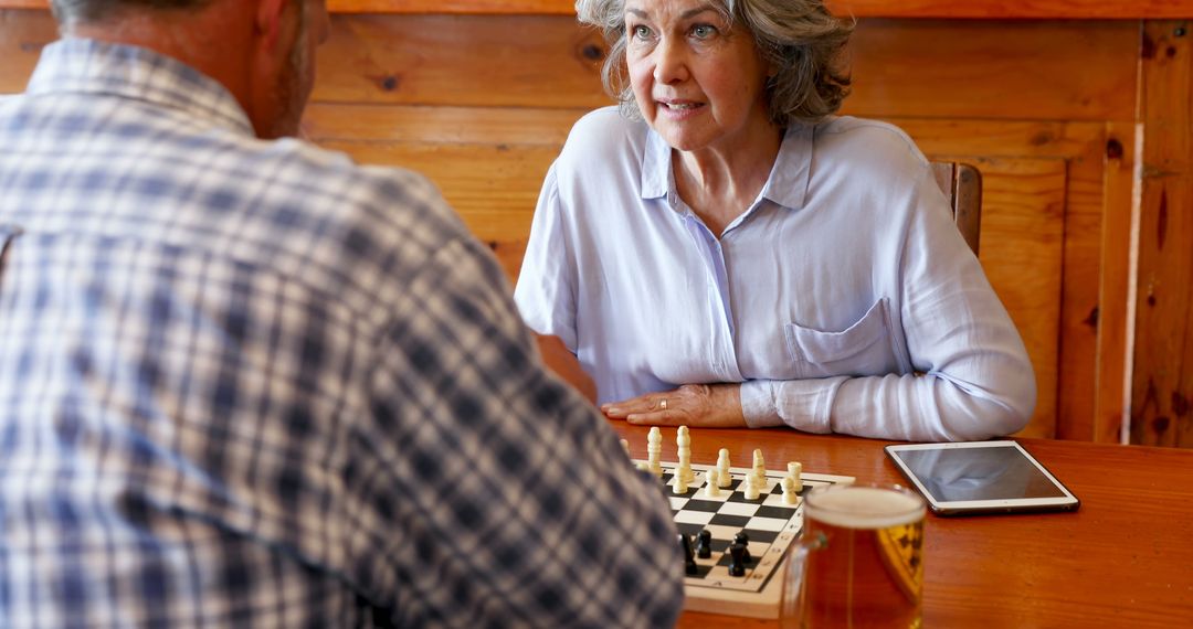 Senior Friends Playing Chess at Wooden Table with Tablet - Free Images, Stock Photos and Pictures on Pikwizard.com