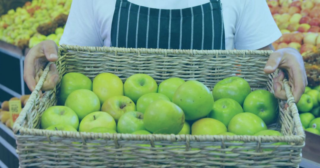 Vendor Arranging Fresh Green Apples in Wicker Basket at Market Stall