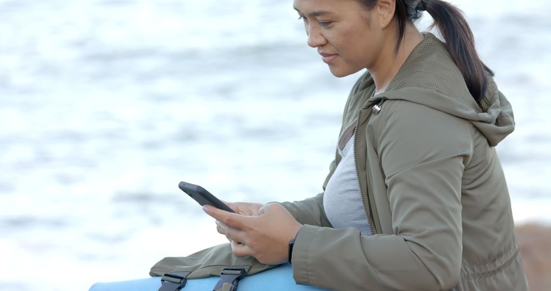 Woman Using Smartphone While Hiking with Backpack and Yoga Mat