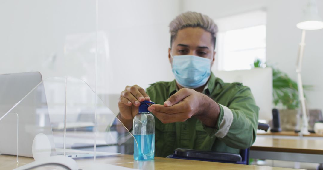 Office worker wearing protective mask using hand sanitizer - Free Images, Stock Photos and Pictures on Pikwizard.com