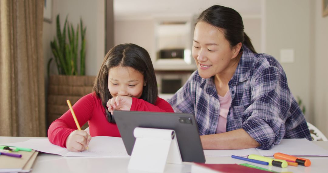 Image of happy asian mother and daughter doing homework together - Free Images, Stock Photos and Pictures on Pikwizard.com