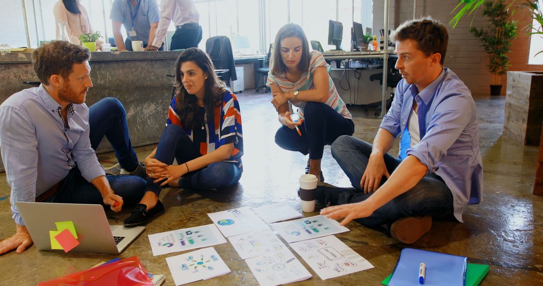 Diverse Professionals Brainstorming on Floor with Documents and Laptop