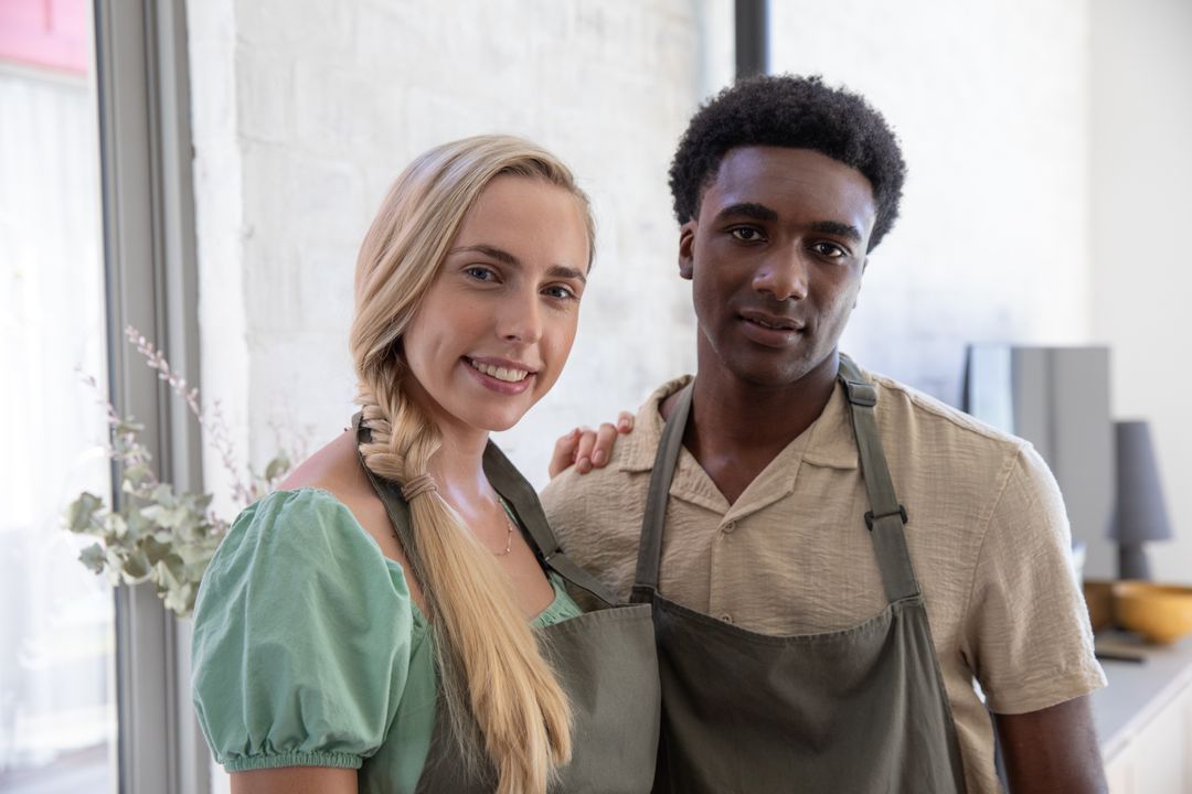 Diverse Couple in Modern Kitchen with Grey Aprons