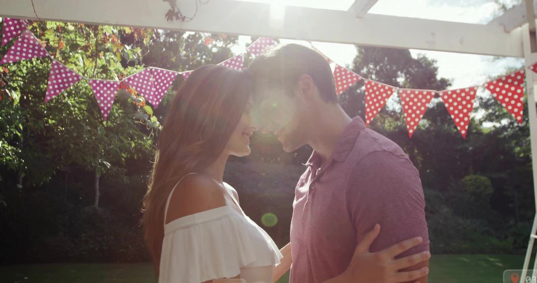 Romantic Couple Embracing Under Pergola With Festive Bunting