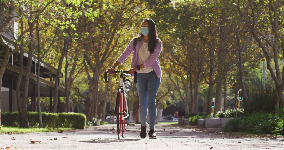 Asian woman wearing face mask with bicycle walking in the park - Free Images, Stock Photos and Pictures on Pikwizard.com