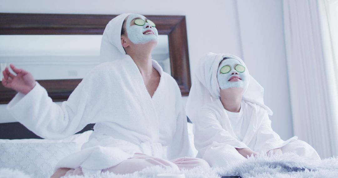 Image of asian mother and daughter in robes pampering with cucumber masks - Free Images, Stock Photos and Pictures on Pikwizard.com