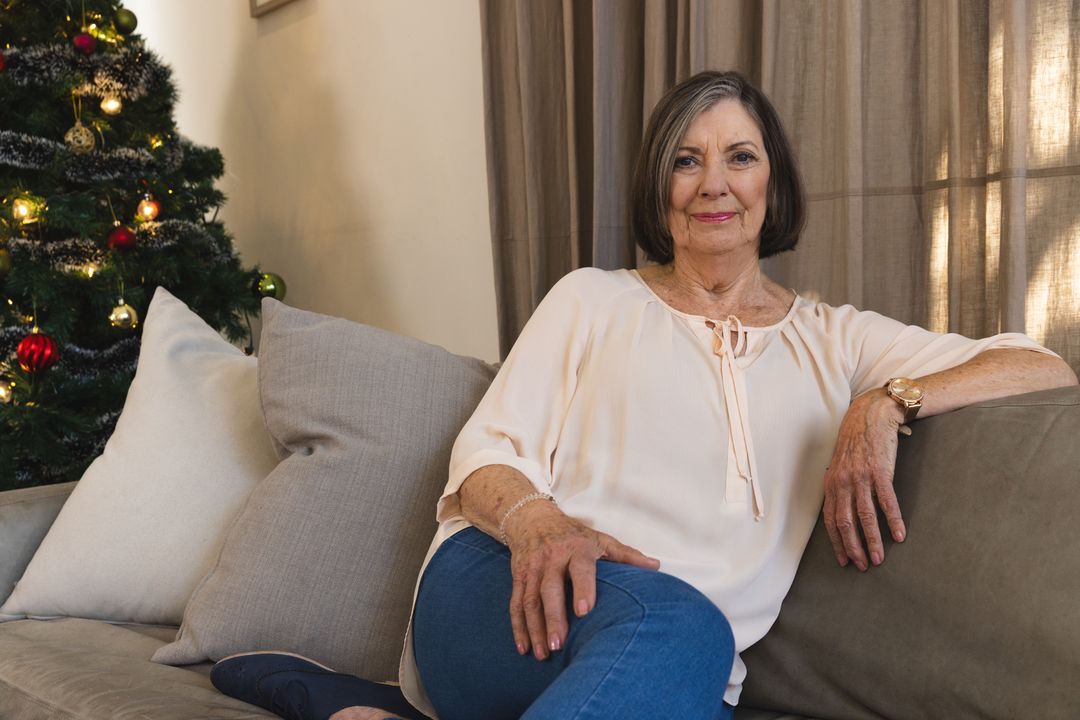 Senior Woman Relaxing on Sofa by Christmas Tree at Home