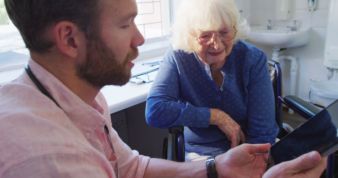 Doctor Consulting Senior Patient Using Tablet in Retirement Home