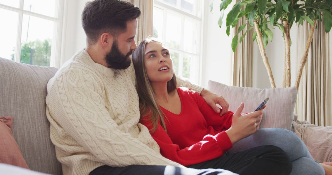 Image of happy caucasian couple siting on sofa and using smartphone - Free Images, Stock Photos and Pictures on Pikwizard.com