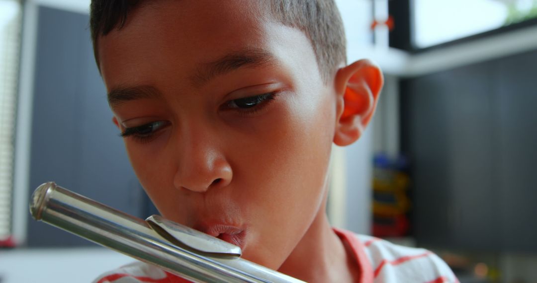 Focused Young Boy Playing Flute in Classroom Instrument Lesson