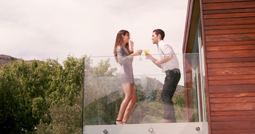 Couple Enjoying Drinks on Modern Balcony with Scenic View - Free Images, Stock Photos and Pictures on Pikwizard.com