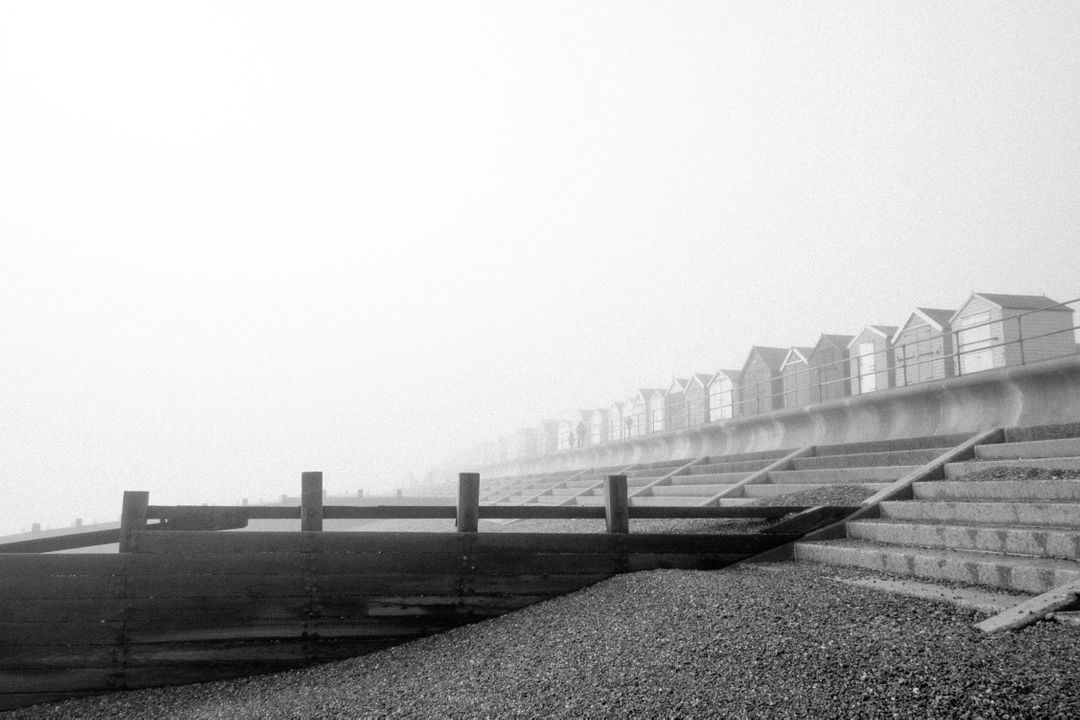 Foggy Coastal Scene with Beach Huts and Wooden Groynes in Black and White - Free Images, Stock Photos and Pictures on Pikwizard.com