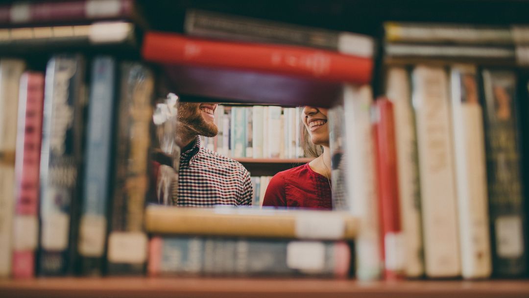 Smiling people behind bookshelf blurred edges full of books