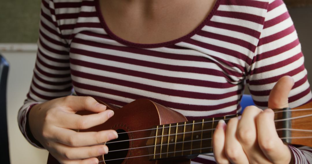 Woman Playing Ukulele Wearing Striped Shirt Indoors - Free Images, Stock Photos and Pictures on Pikwizard.com