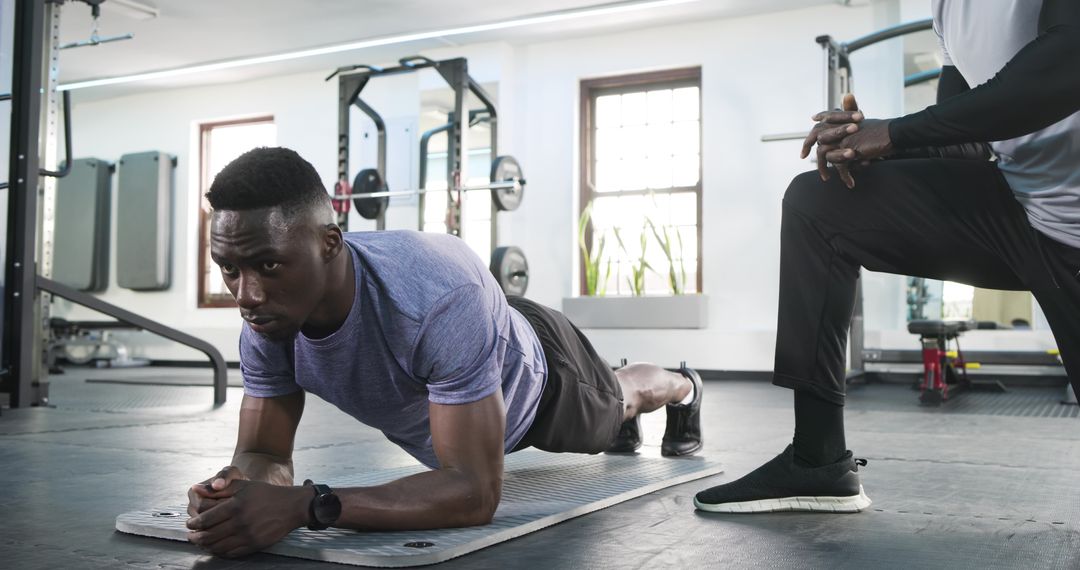 Personal Trainer Coaching Client Performing Plank at Gym