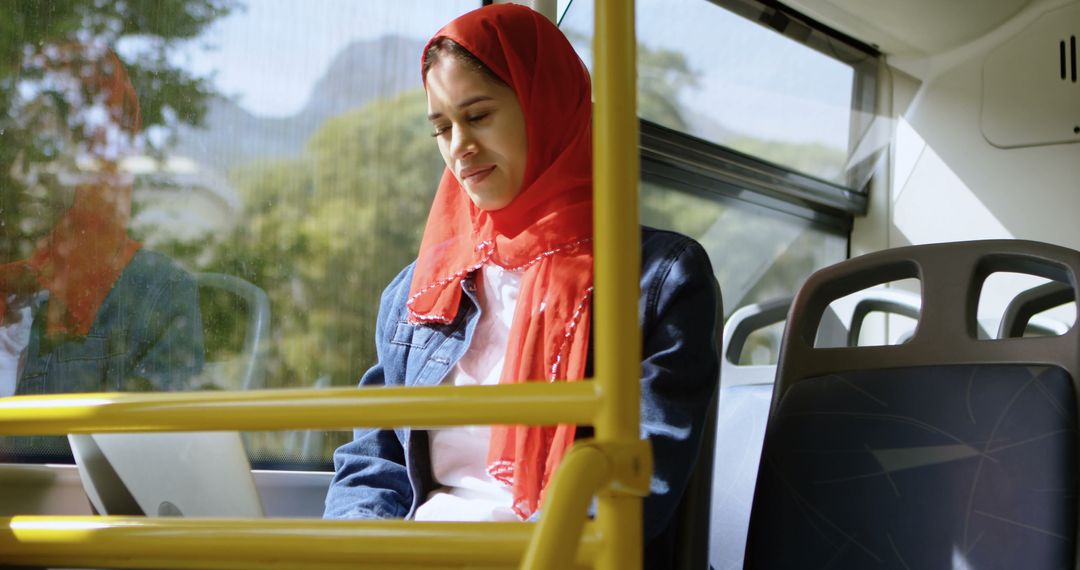 Young Woman Wearing Red Hijab Working on Laptop on Bus - Free Images, Stock Photos and Pictures on Pikwizard.com