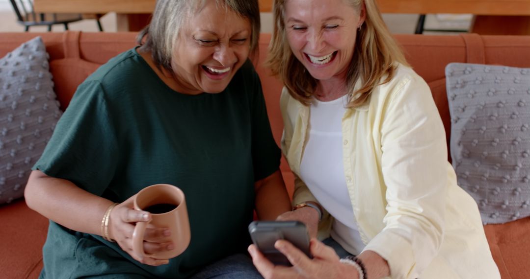 Smiling Friends Enjoying Mobile Content Together on Comfortable Sofa