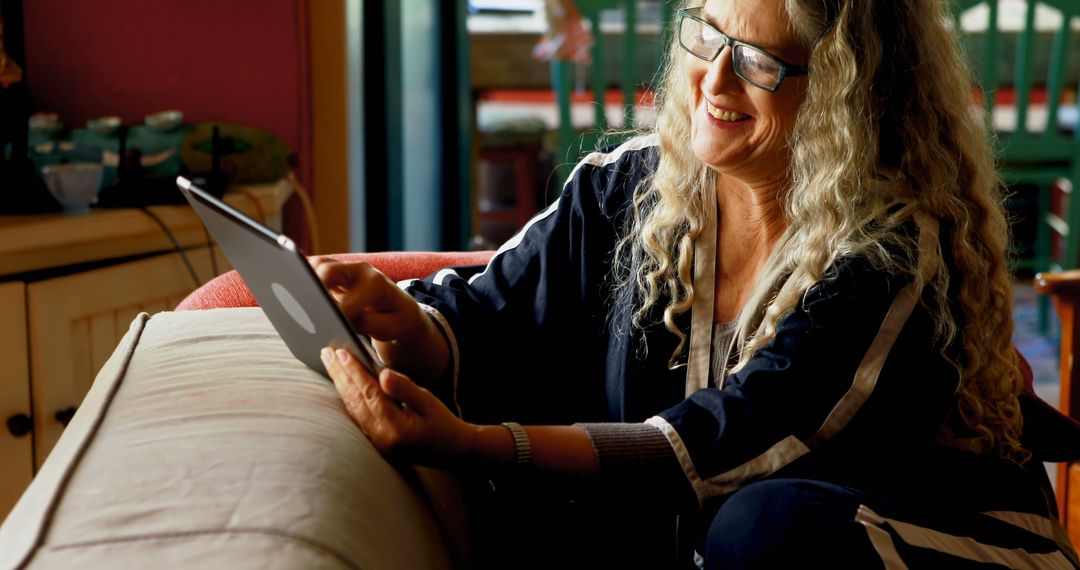 Woman with long curly hair using tablet at home - Free Images, Stock Photos and Pictures on Pikwizard.com