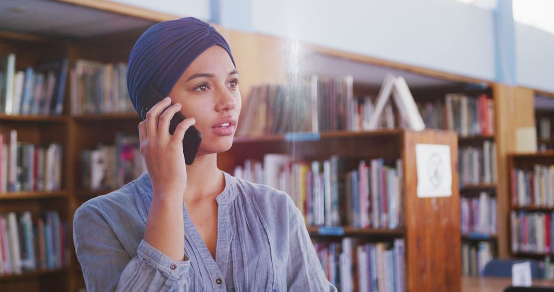 Young Woman Wearing Headscarf Talking on Phone in Library - Free Images, Stock Photos and Pictures on Pikwizard.com