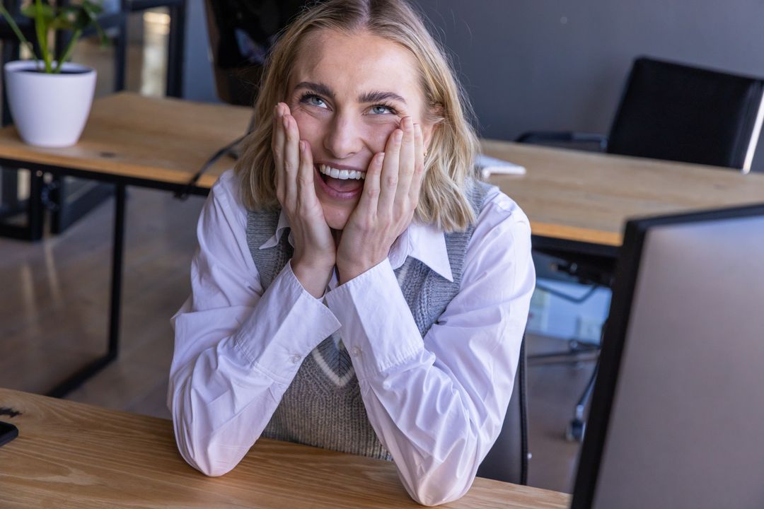 Smiling Woman Cheering at Office Desk with Computer