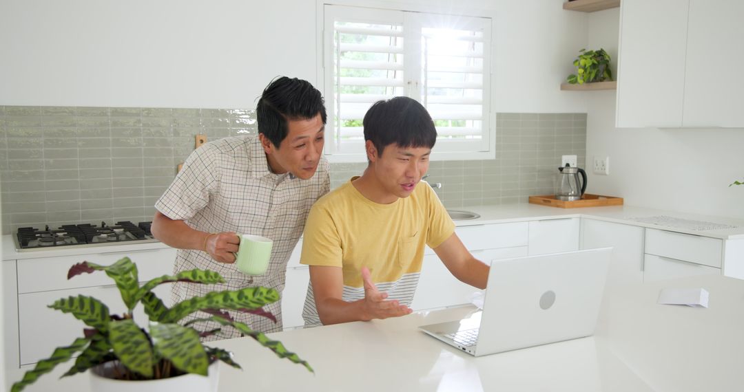 Father and Son Enjoying Laptop Time in Modern Kitchen