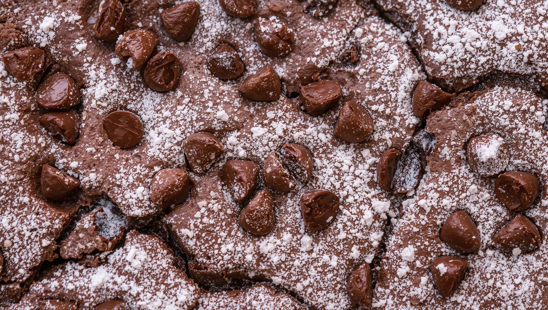 Fudgy Chocolate Brownie Closeup with Melting Chocolate Chips and Powdered Sugar Dusting