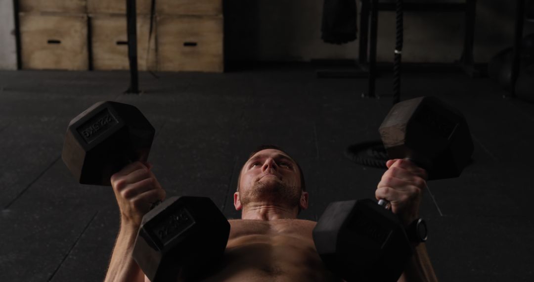 Athletic Man Lifting Dumbbells at Gym for Strength Training