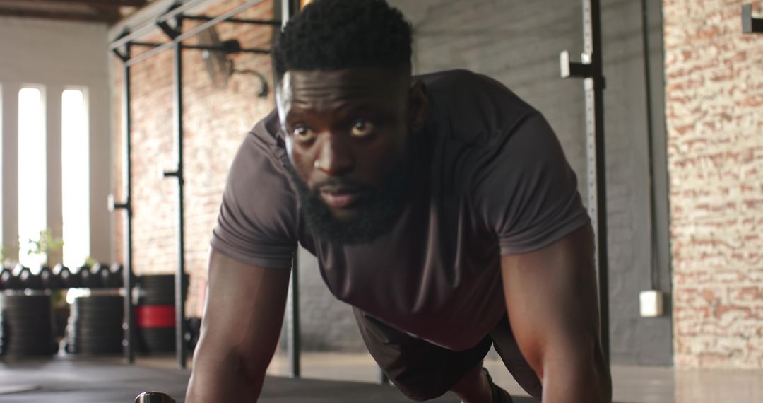 Athletic Man Focused During Plank Push-Up Exercise in Modern Gym