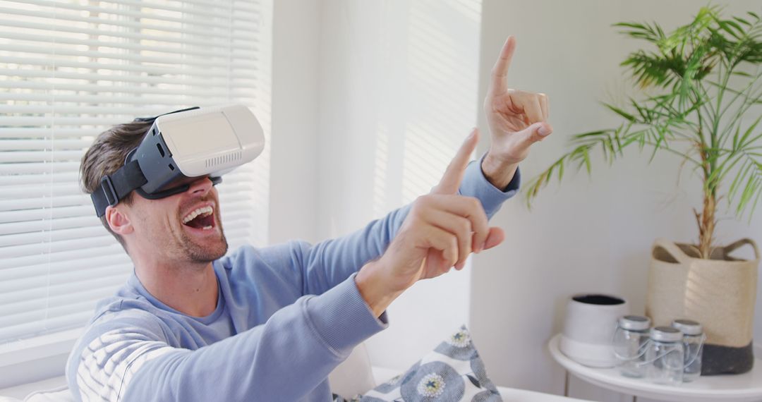 Man Experiencing Virtual Reality at Home, Laughing and Pointing - Free Images, Stock Photos and Pictures on Pikwizard.com