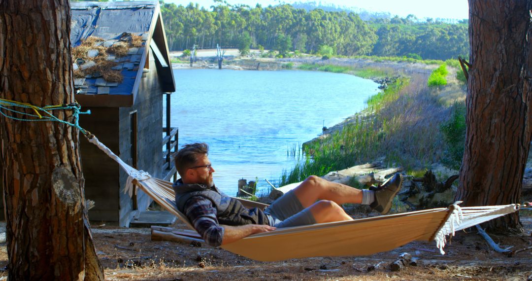 Man Relaxing in Hammock by Lake Cabin in Forest - Free Images, Stock Photos and Pictures on Pikwizard.com